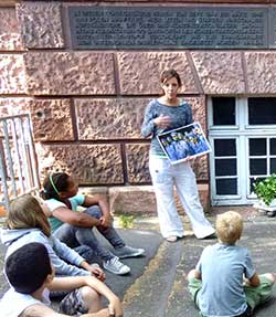 Nadja Kaiser von der KZ-Gedenkstätte Mannheim-Sandhofen mit den Schülerinnen und Schülern vor der Gedenktafel.